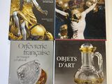 trois livres posés sur une table blanche, accompagnés d'un vase doré et d'autres objets