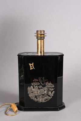 une bouteille noire ornée d'un emblème doré, à côté d'une paire de ciseaux