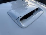 the hood of a white car with a hole in the hood