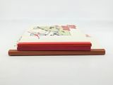a book with a red cover sitting on top of a wooden stand