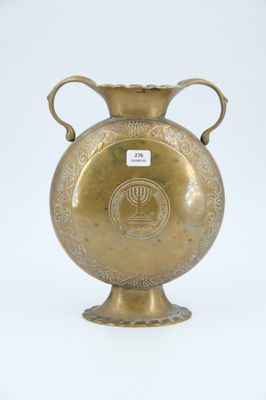 a gold vase that is sitting on a white surface