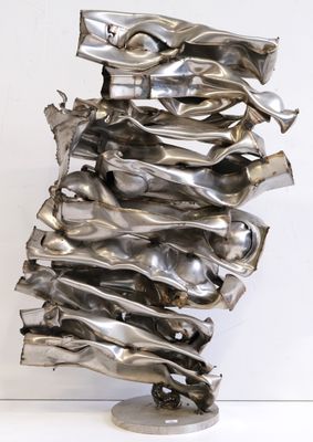 sculpture en argent représentant une grande pile d'objets métalliques posée sur une surface blanche