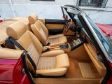the interior of a red convertible car with tan leather seats