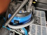 a blue and black vacuum in the middle of a pile of assorted items