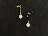a pair of pearl earrings on a black background