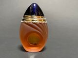 an orange glass egg with a gold ring on top