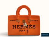 an orange hermes paris handbag with a logo on the front