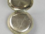 a small silver pocket watch with a key in it