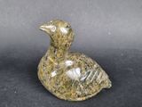 marble duck figurine on a black surface with a gray background