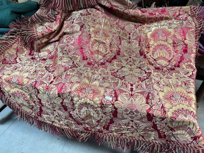 une couverture rouge et dorée posée sur une chaise dans une pièce