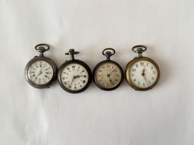 four antique pocket watches are lined up on a white surface