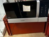 a person holding a piece of paper in front of a microwave
