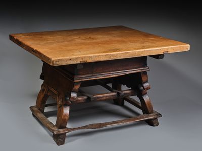 an old wooden table with a wooden top sitting on a gray surface