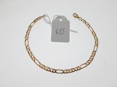 a close up of a gold chain bracelet with a tag on it