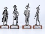 three silver metal figurines of men with hats and tails on wooden bases
