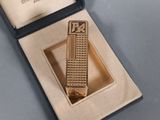 a gold tie bar with a clock on it in a box
