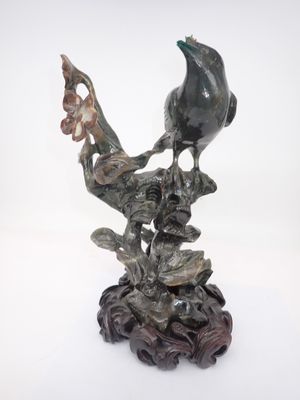 statue représentant un oiseau perché sur une branche, tenant une fleur dans son bec