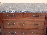 a marble top chest of drawers in the corner of a room