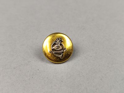 un gros plan d'un bouton doré sur une surface blanche