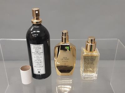 trois flacons de parfum posés sur une étagère transparente
