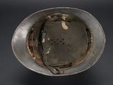 an old helmet with a hole in the middle of it on a black surface