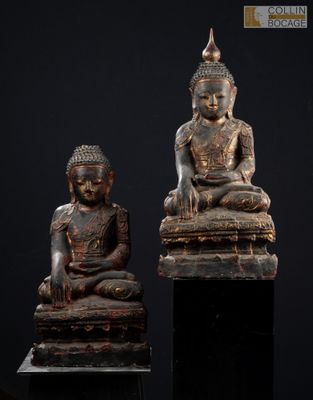 deux statues de bouddhas assis sur un socle noir
