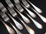 a lot of silver forks and spoons on a table