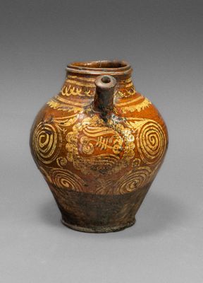 a brown vase with designs on it sitting on a table