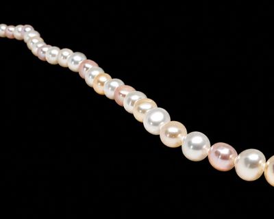 a close up of a pearl necklace on a black background