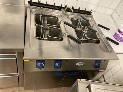 stainless steel counter top with three deep fryers on each side of it