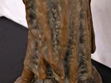 bronze statue of a woman holding a bird on a black surface