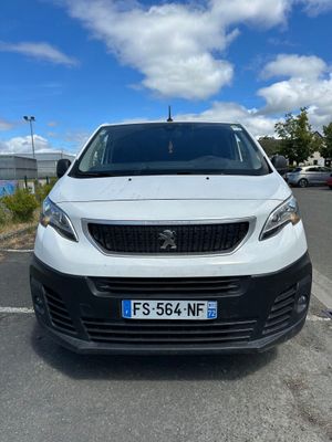 une petite camionnette blanche garée dans un parking