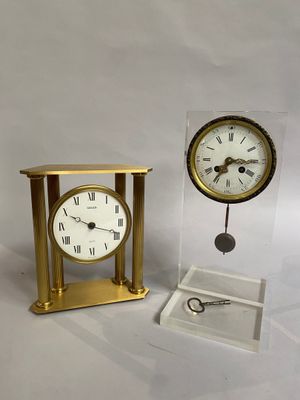 une petite horloge posée à côté d'une autre, plus petite, sur une table