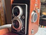a brown and black camera sitting on top of a brown case