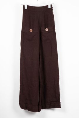 Le pantalon marron est suspendu à un cintre contre un mur blanc.