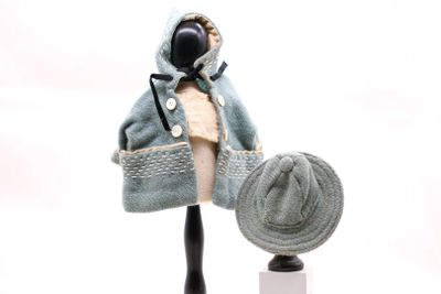 un mannequin coiffé d'un chapeau et vêtu d'un manteau, posé sur un socle