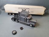 a toy semi truck with a semi trailer in the background