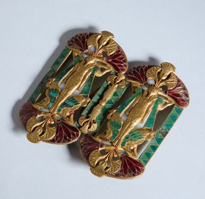 deux broches dorées et vertes sur un fond blanc
