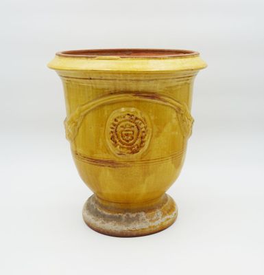 un vase jaune posé sur un socle, sur une surface blanche