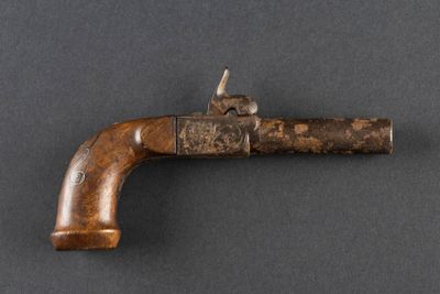 un vieux pistolet avec une poignée en bois sur une surface grise