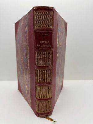 un vieux livre à la couverture rouge posé sur une table blanche