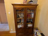 a wooden cabinet in the corner of a room with books on the floor