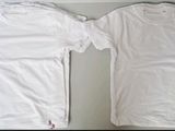 two white t - shirts sitting on top of a table next to each other