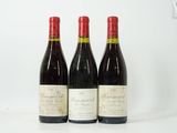trois bouteilles de vin rouge sont posées sur une surface blanche