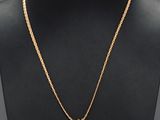 a gold necklace with a coin on a mannequin neck