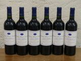 six bouteilles de vin rouge alignées sur une table en bois