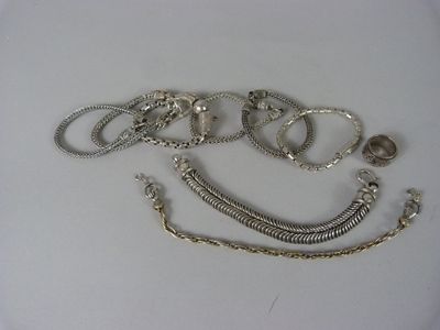 de nombreux bracelets en argent posés sur une surface blanche