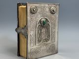 un vieux livre en argent orné d'une pierre verte au centre