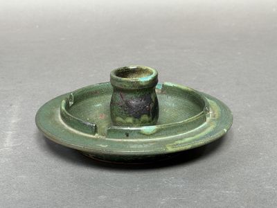 une petite assiette verte sur laquelle est posé un bougeoir