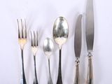 five forks, a spoon, and a knife on a white surface